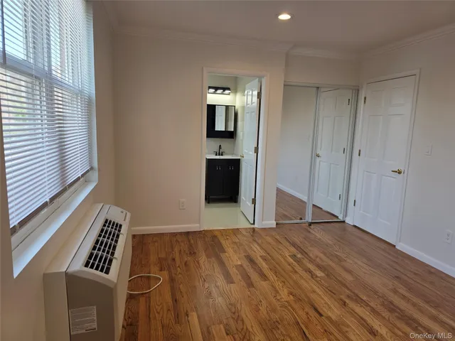 a view of an empty room with a window and wooden floor