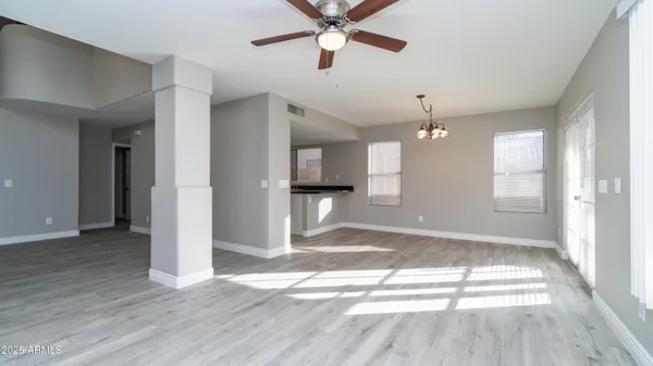 a view of empty room with wooden floor and fan