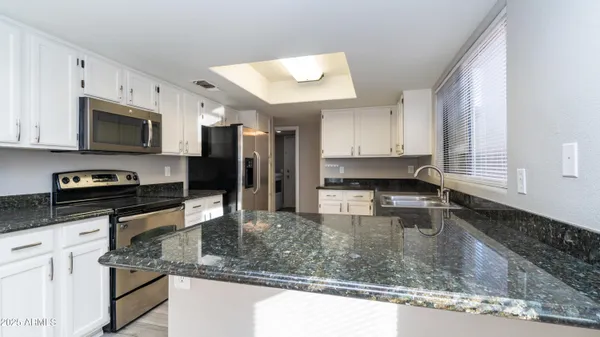 a kitchen with stainless steel appliances kitchen island granite countertop a sink dishwasher stove and microwave with wooden floor