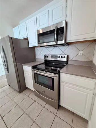 a kitchen with granite countertop white cabinets and stainless steel appliances