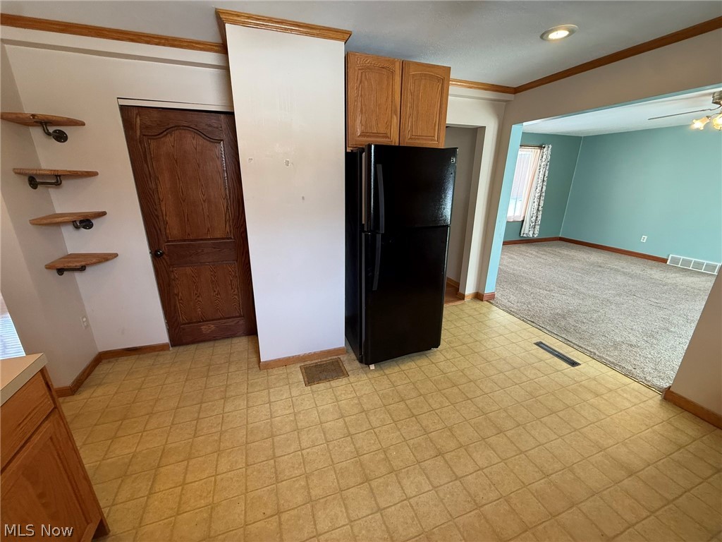 6784 Old Zoarville Road Northeast Dover, OH 44622 - Photo 12 of 50 Kitchen with freestanding refrigerator, crown molding, light countertops, light carpet, and ceiling fan
