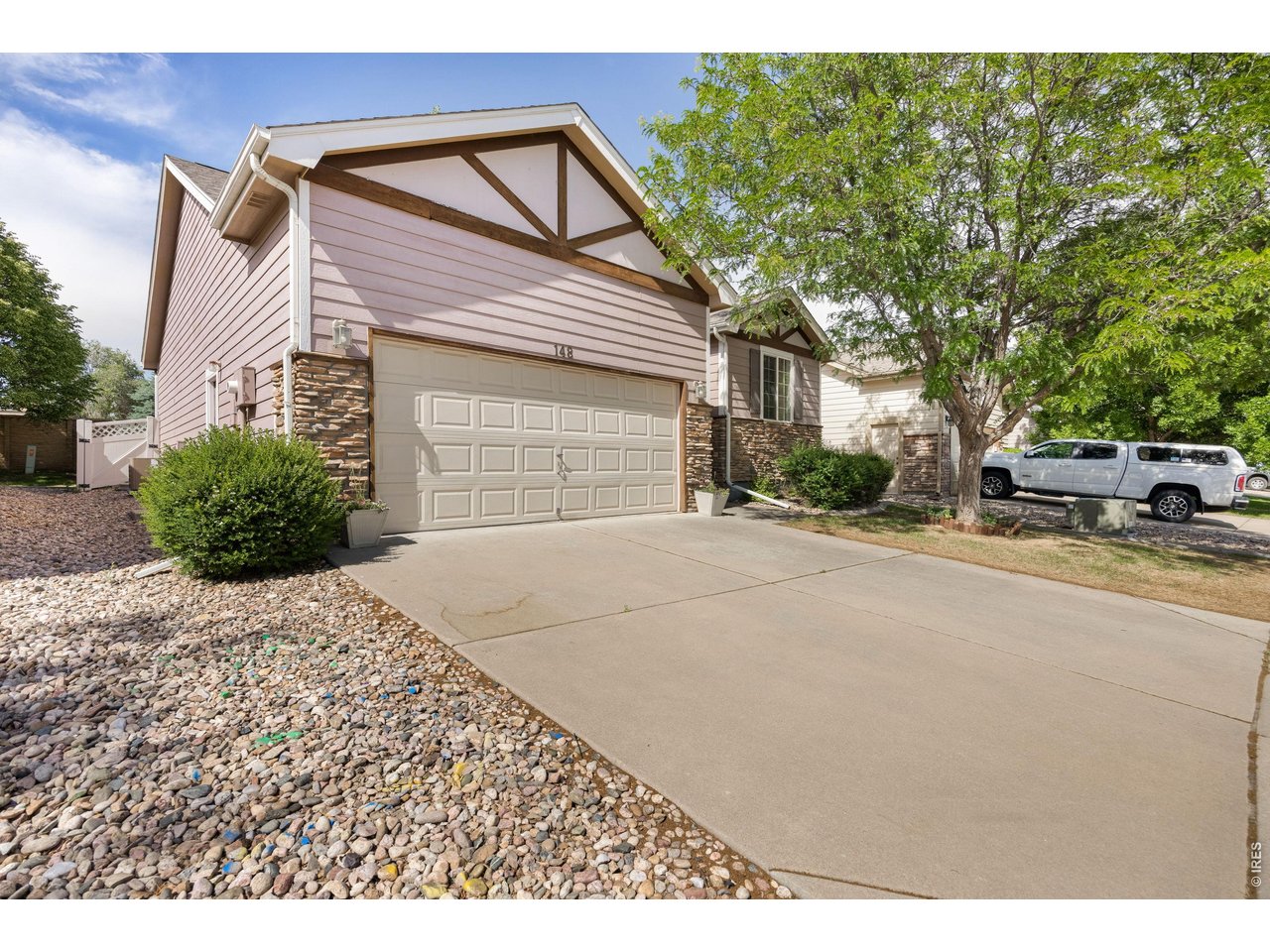 148 Beacon Way Windsor, CO 80550 - Photo 2 of 36 Angled front exterior view showcasing the home's curb appeal, extended driveway, low maintenance landscaping, stone detailing, and side yard access with vinyl fencing.