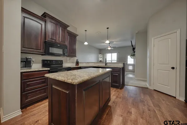 a kitchen with stainless steel appliances granite countertop a kitchen island a stove and a wooden floors