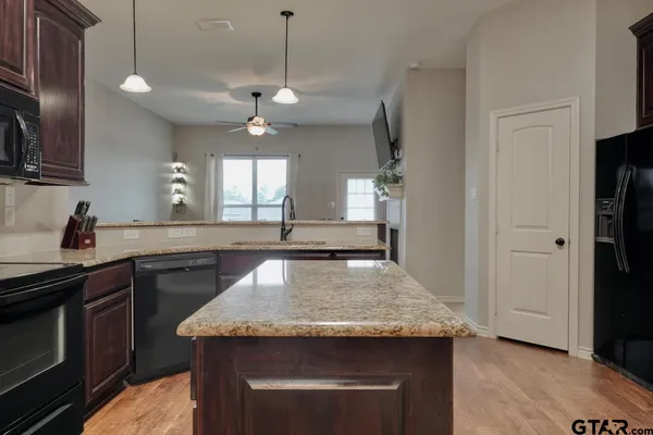 a kitchen with granite countertop kitchen island a sink appliances and a counter top space
