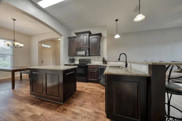 a kitchen with stainless steel appliances granite countertop a sink a stove and a refrigerator