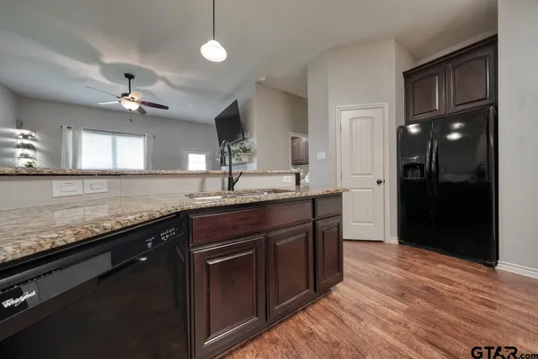 a kitchen with granite countertop a sink cabinets and stainless steel appliances