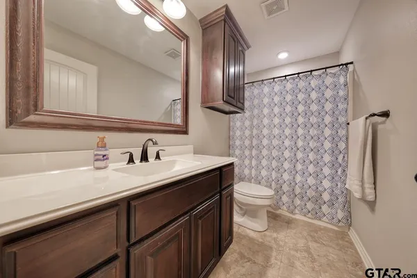 a bathroom with a granite countertop sink toilet and a mirror