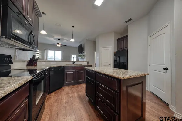 a kitchen with stainless steel appliances granite countertop sink stove top oven and cabinets