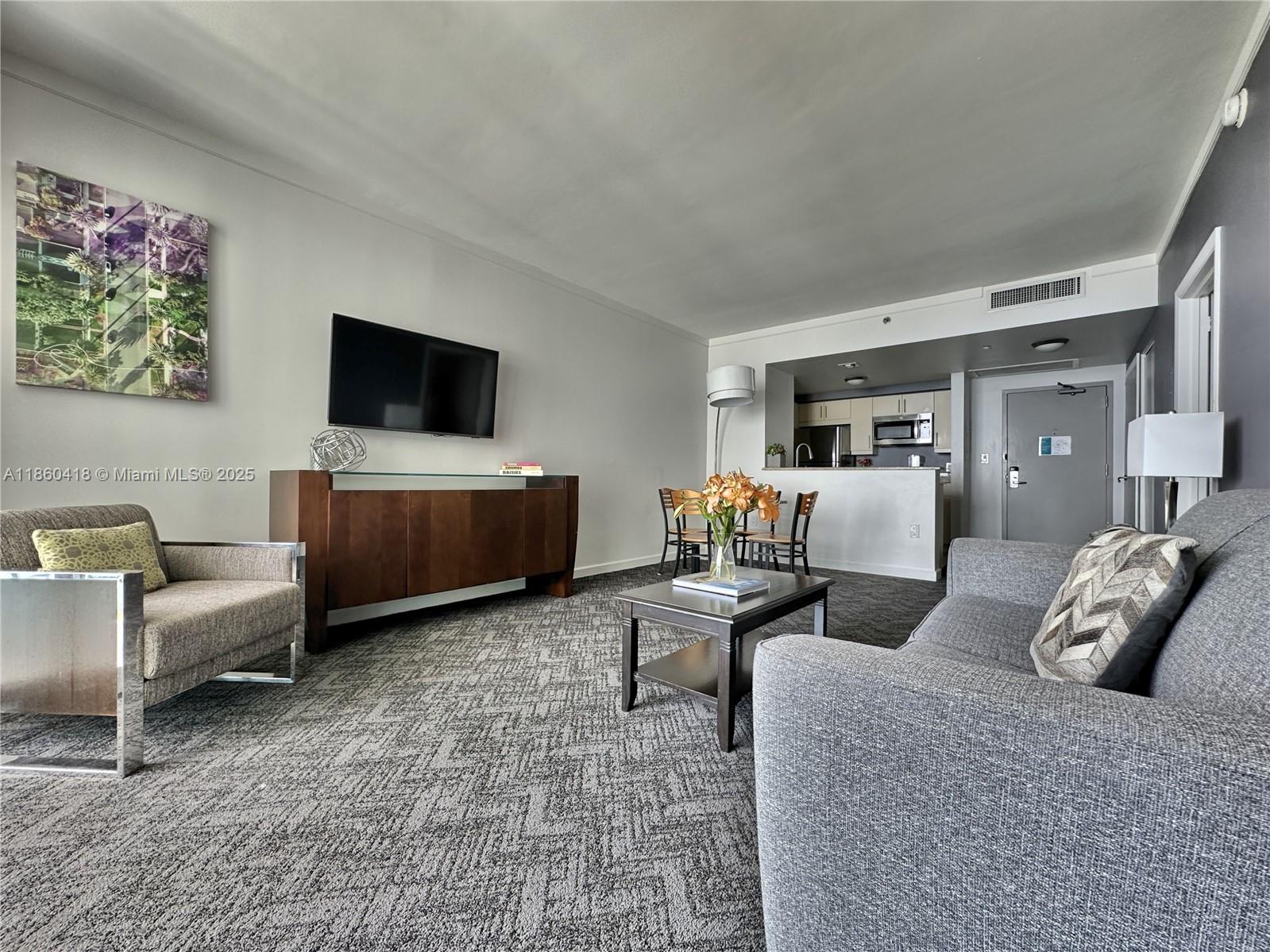 2889 McFarlane Road, Unit 1814 Miami, FL 33133 - Photo 5 of 12 a living room with furniture and a flat screen tv