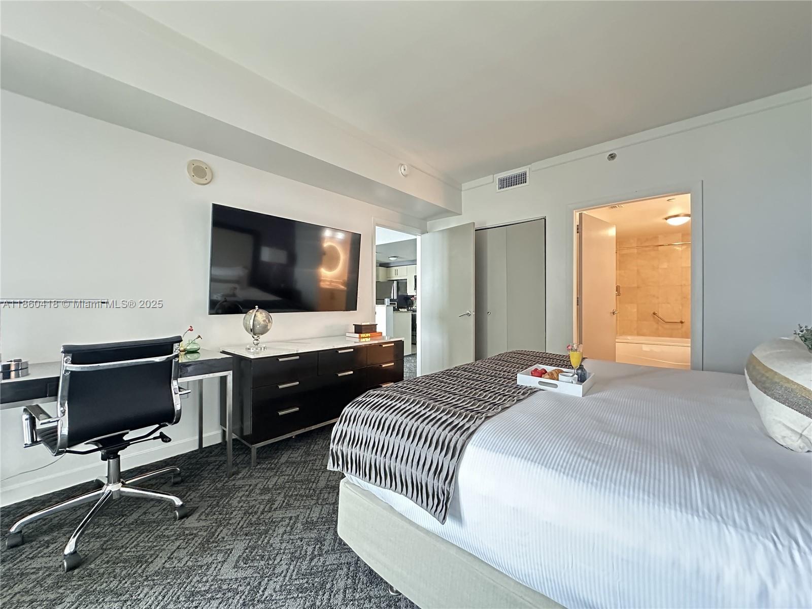 2889 McFarlane Road, Unit 1814 Miami, FL 33133 - Photo 9 of 12 a bedroom with a bed and a flat screen tv