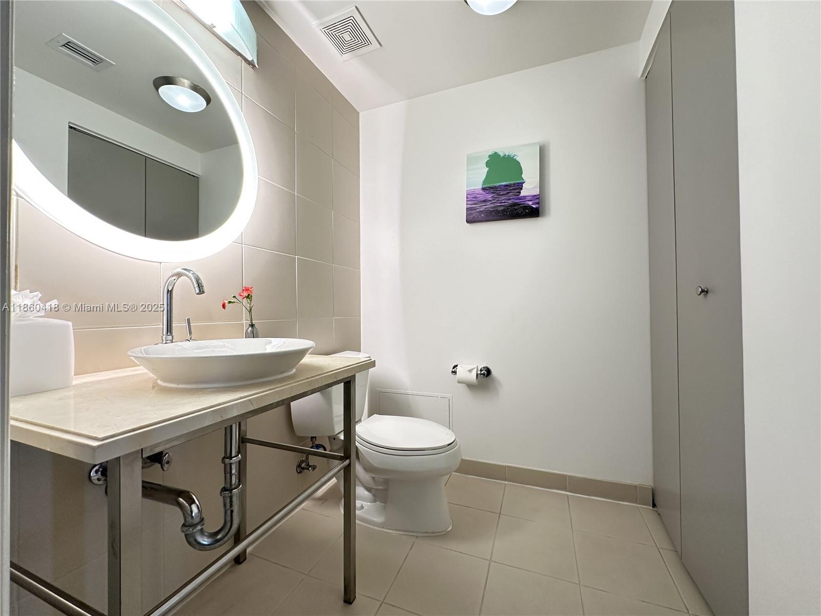 2889 McFarlane Road, Unit 1814 Miami, FL 33133 - Photo 10 of 12 a bathroom with a toilet a sink and mirror