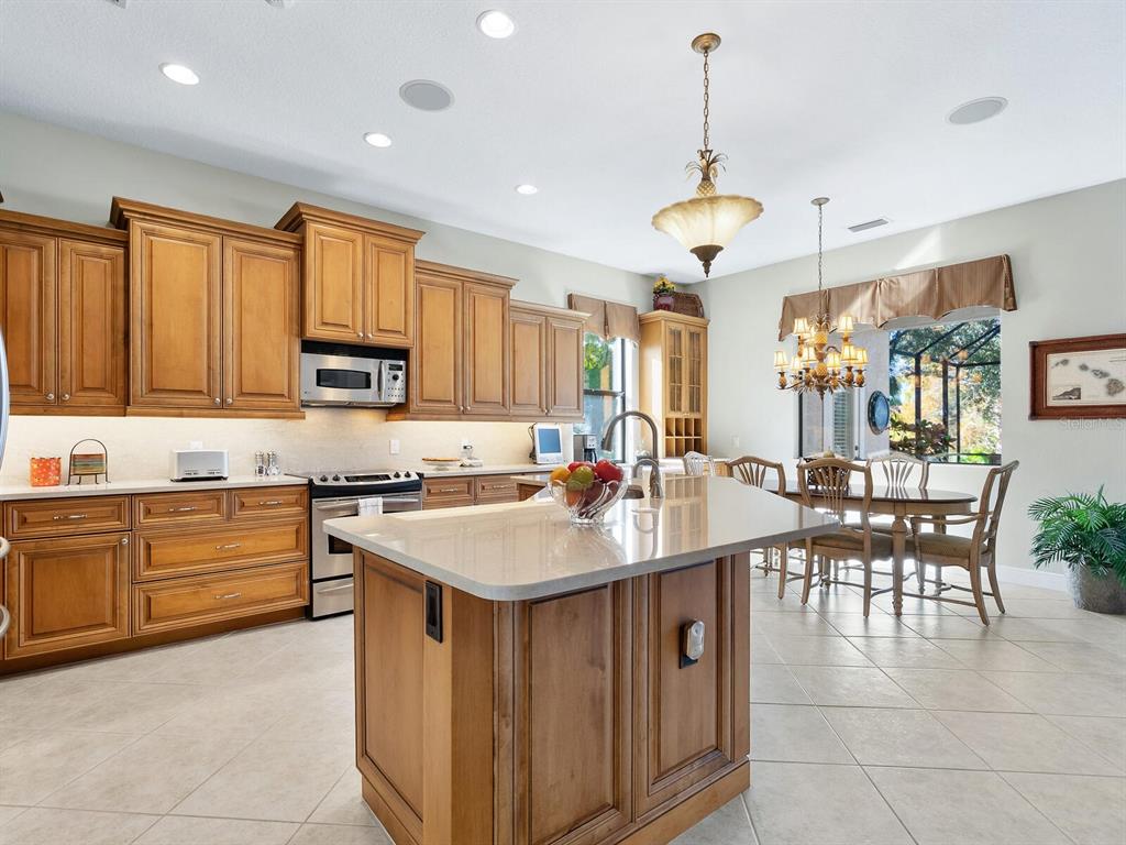13911 Siena Loop Lakewood Ranch, FL 34202 - Photo 12 of 63 a kitchen with stainless steel appliances granite countertop a sink a stove top oven a dining table and chairs