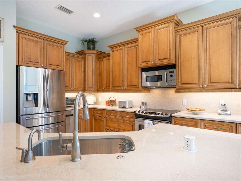 13911 Siena Loop Lakewood Ranch, FL 34202 - Photo 14 of 63 a kitchen with stainless steel appliances granite countertop a refrigerator and a sink