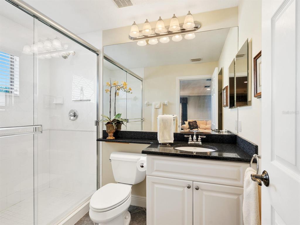 13911 Siena Loop Lakewood Ranch, FL 34202 - Photo 37 of 63 a bathroom with a granite countertop sink a mirror a toilet and shower