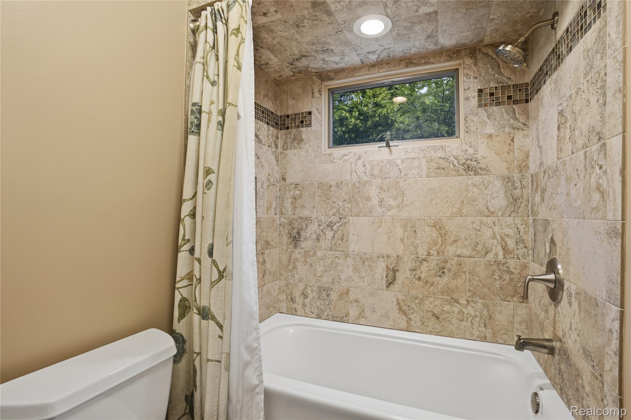 68345 Romeo Plank Road Ray, MI 48096 - Photo 41 of 52 Bathtub with stone tile surround, brushed nickel fixtures, recessed lighting, and an upper window