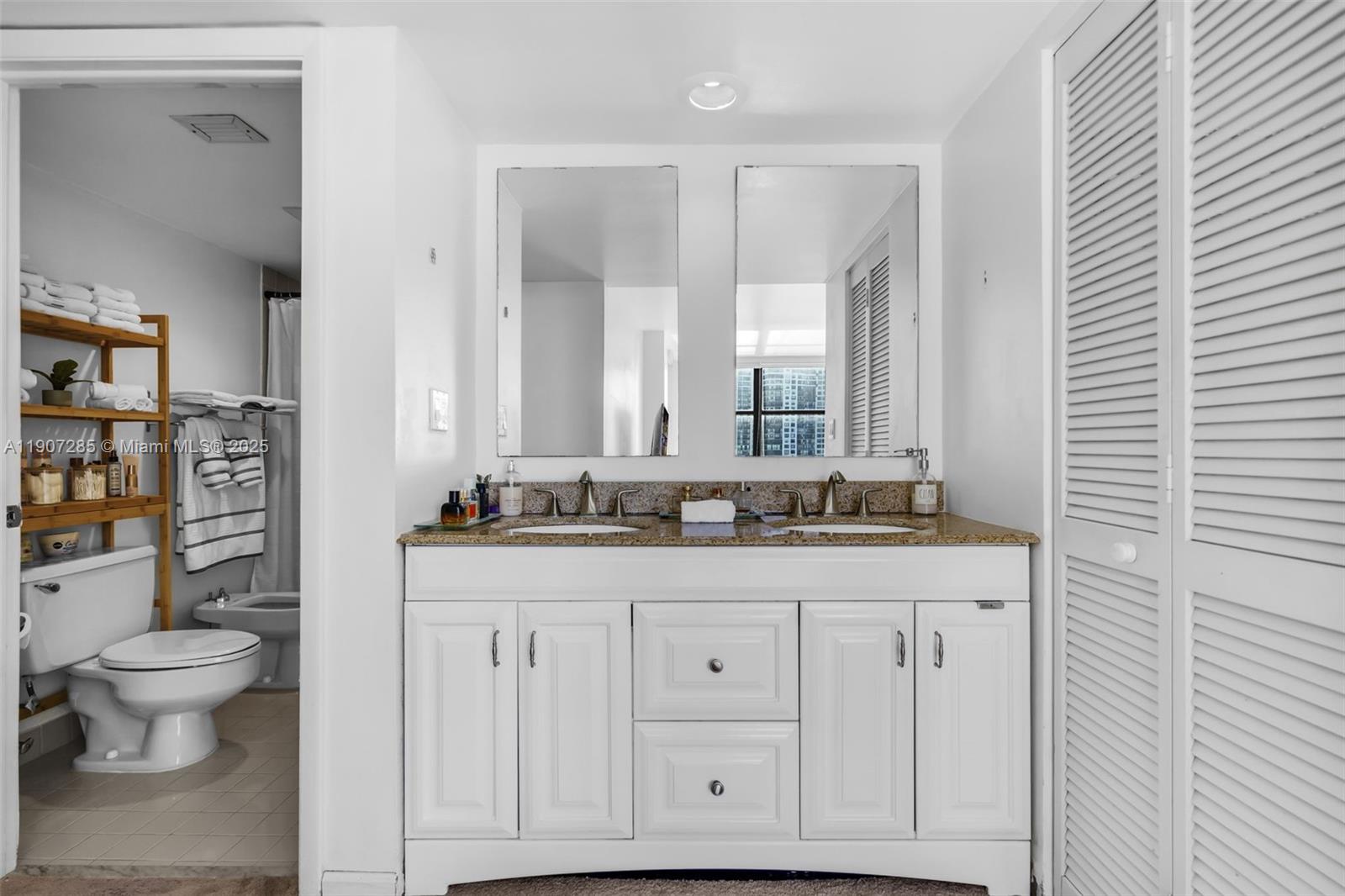 1925 Brickell Avenue, Unit 1811 Miami, FL 33129 - Photo 23 of 63 a bathroom with a granite countertop double vanity sink a mirror and a toilet