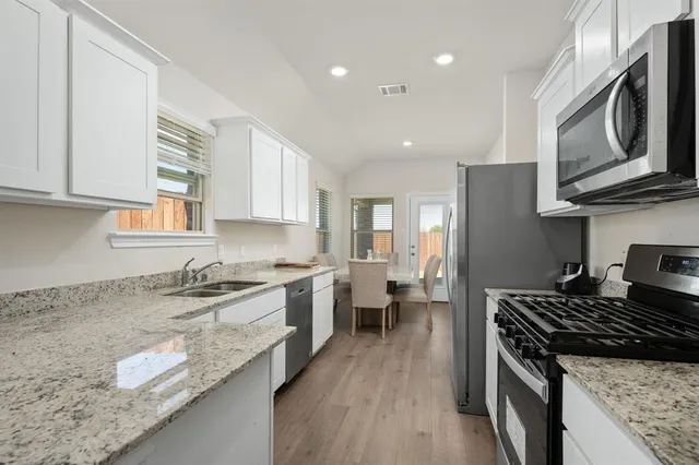 a kitchen with granite countertop stainless steel appliances window a sink and a counter