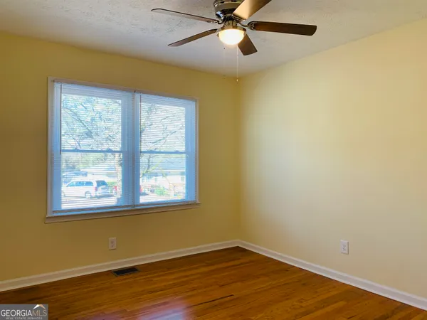 a view of an empty room with wooden floor and a window
