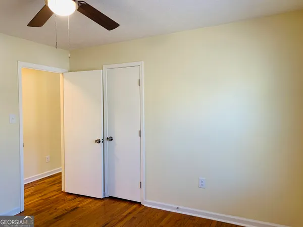 a view of a room with wooden floor and ceiling fan