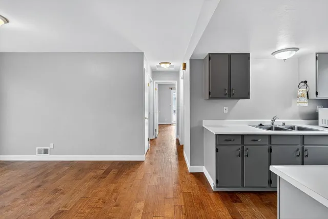 a view with cabinets a sink wooden floor and a mirror