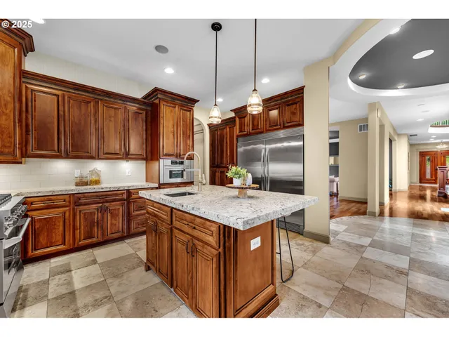 a kitchen with stainless steel appliances granite countertop a stove a sink dishwasher and a refrigerator with wooden cabinets