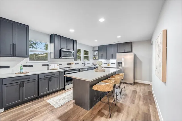 a kitchen with stainless steel appliances granite countertop a sink stove refrigerator and cabinets