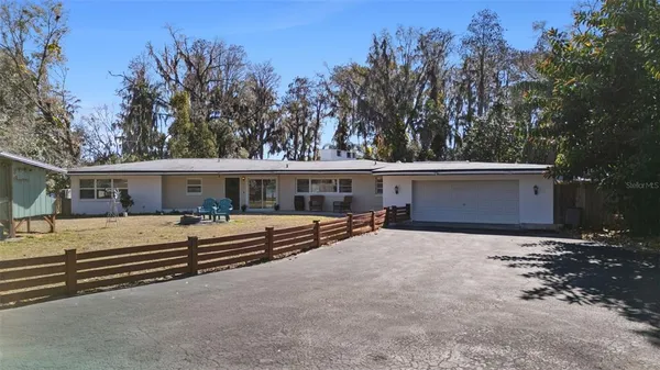 a view of a house with a yard and large trees