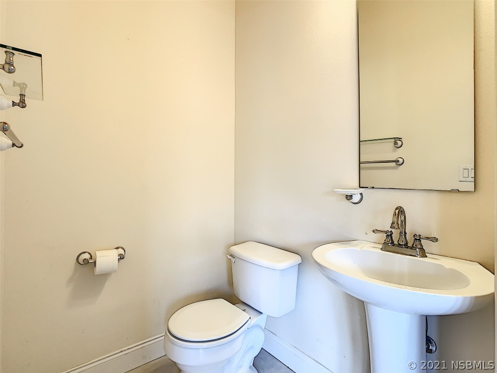 6273 Engram Road New Smyrna Beach, FL 32169 - Photo 24 of 34 a bathroom with a toilet a sink and mirror