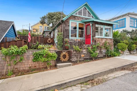 a front view of a house with a yard and potted plants