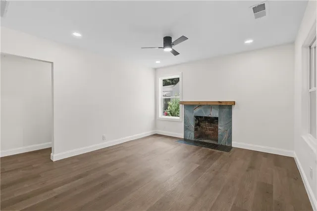 a view of an empty room with wooden floor fireplace and a window