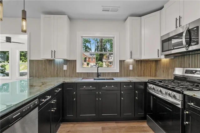 a kitchen with stainless steel appliances granite countertop a sink stove and cabinets
