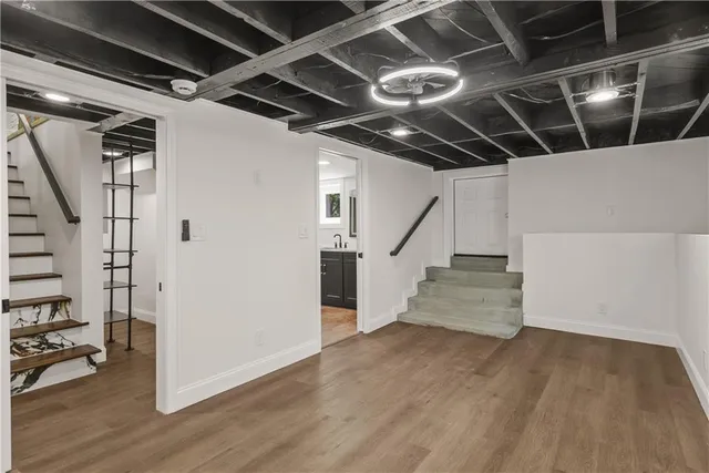 a view of an empty room with wooden floor and stairs