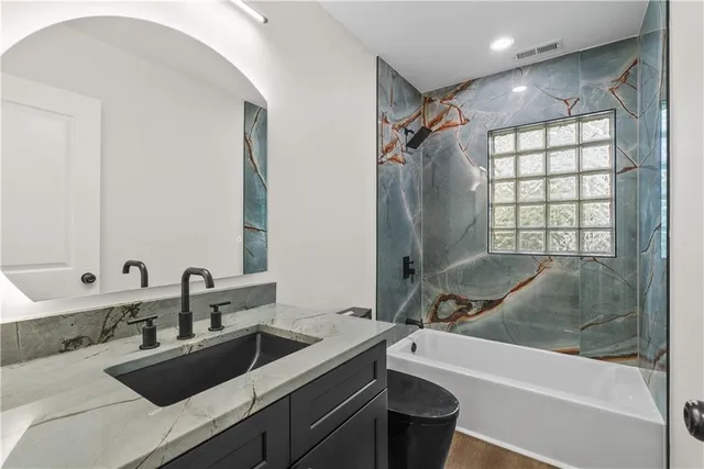 a bathroom with a granite countertop sink toilet and shower