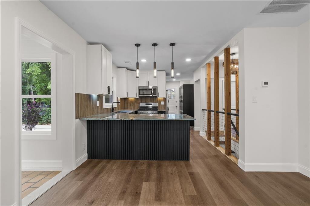 1658 Altadena Place Southwest Atlanta, GA 30311 - Photo 9 of 47 a kitchen with kitchen island granite countertop a refrigerator cabinets and wooden floor