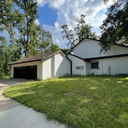 a view of a yard in front of a house with large trees