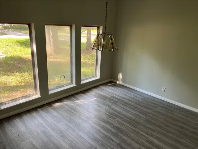 an empty room with wooden floor fan and windows