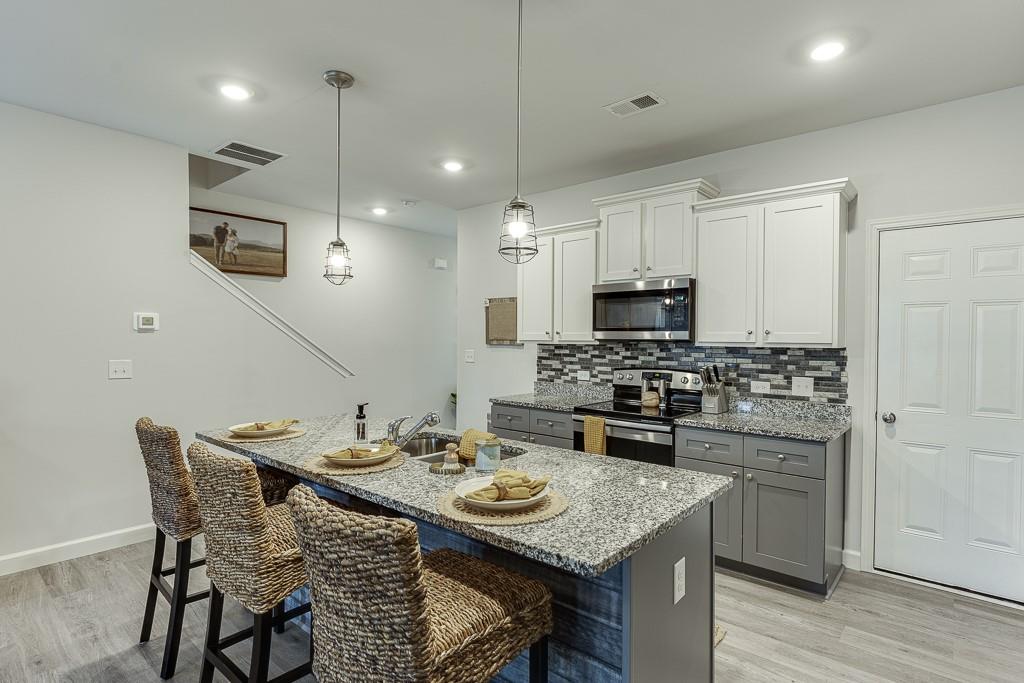 3712 Abbey Way Gainesville, GA 30507 - Photo 10 of 44 a kitchen with stainless steel appliances kitchen island granite countertop a kitchen island a stove a table and chairs