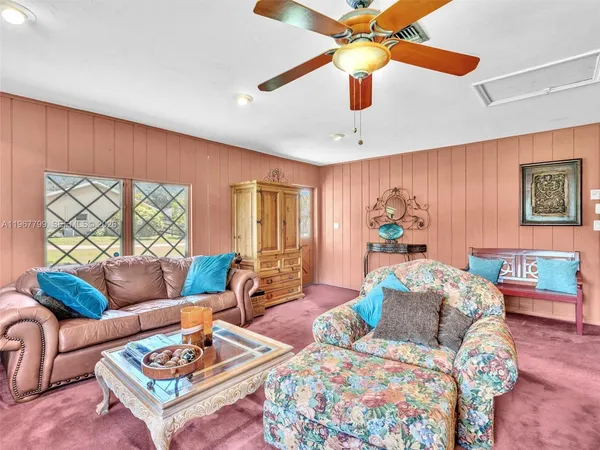 a living room with furniture a flat screen tv and a floor to ceiling window