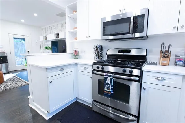 a kitchen with stainless steel appliances a stove microwave and white cabinets