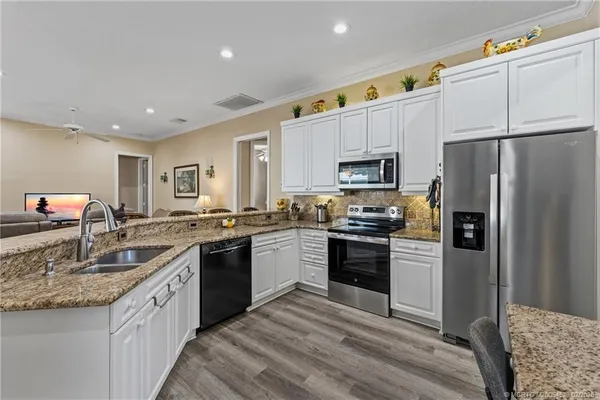 a kitchen with granite countertop a sink stainless steel appliances and white cabinets