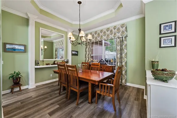 a dining room with wooden floor a chandelier a wooden table and chairs