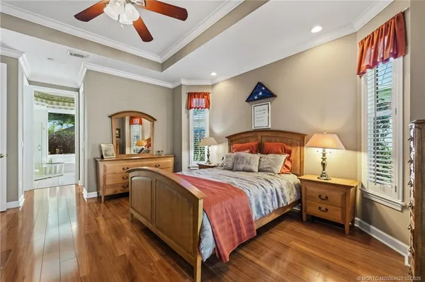 a bedroom with a bed and a large window with wooden floor