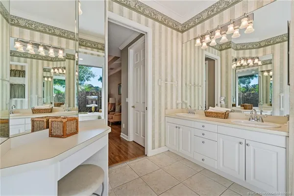 a large bathroom with a double vanity sink a large mirror and a bathtub next to a window