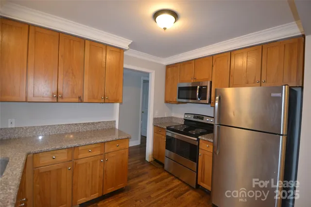 a kitchen with granite countertop stainless steel appliances a refrigerator stove top oven and cabinets