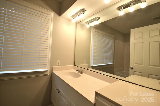 a bathroom with a granite countertop sink and a large mirror