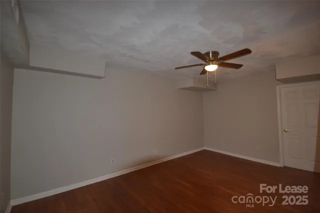 an empty room with wooden floor and fan