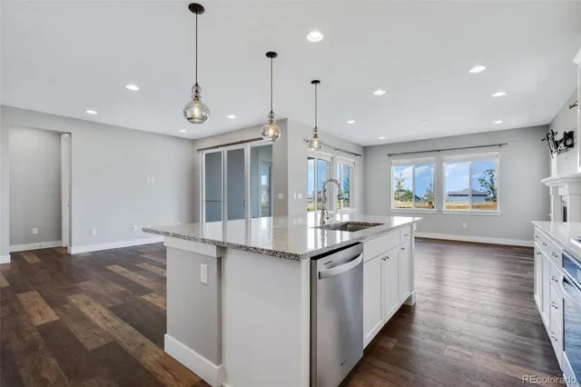 a kitchen with stainless steel appliances granite countertop a sink and a wooden floor