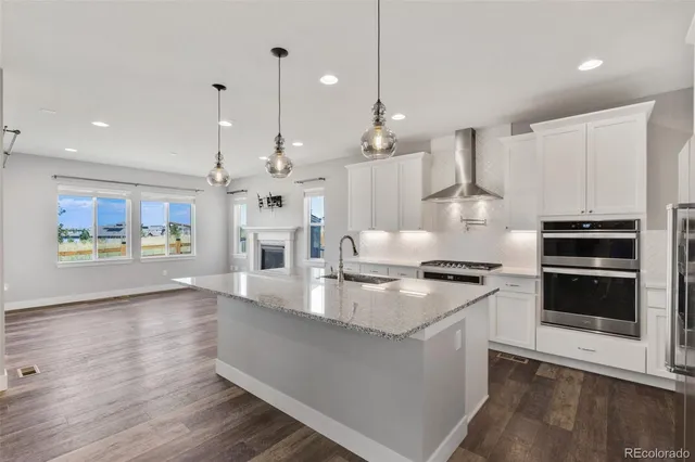 a large kitchen with stainless steel appliances a large counter top a stove a chimney and a wooden floor