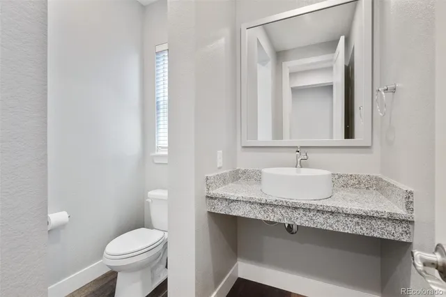 a bathroom with a granite countertop sink and a toilet