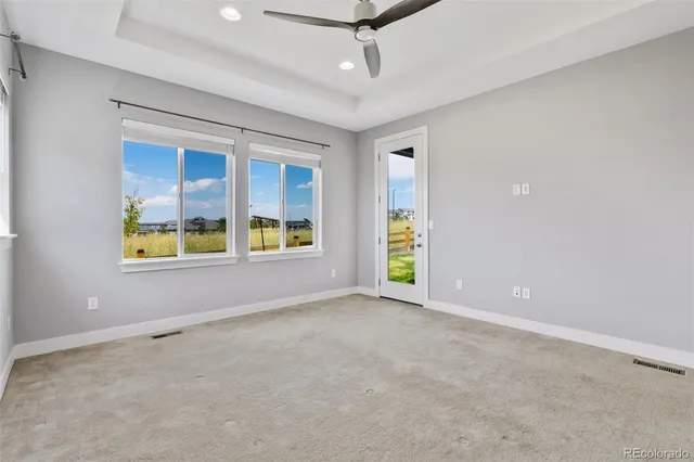 an empty room with windows and chandelier fan